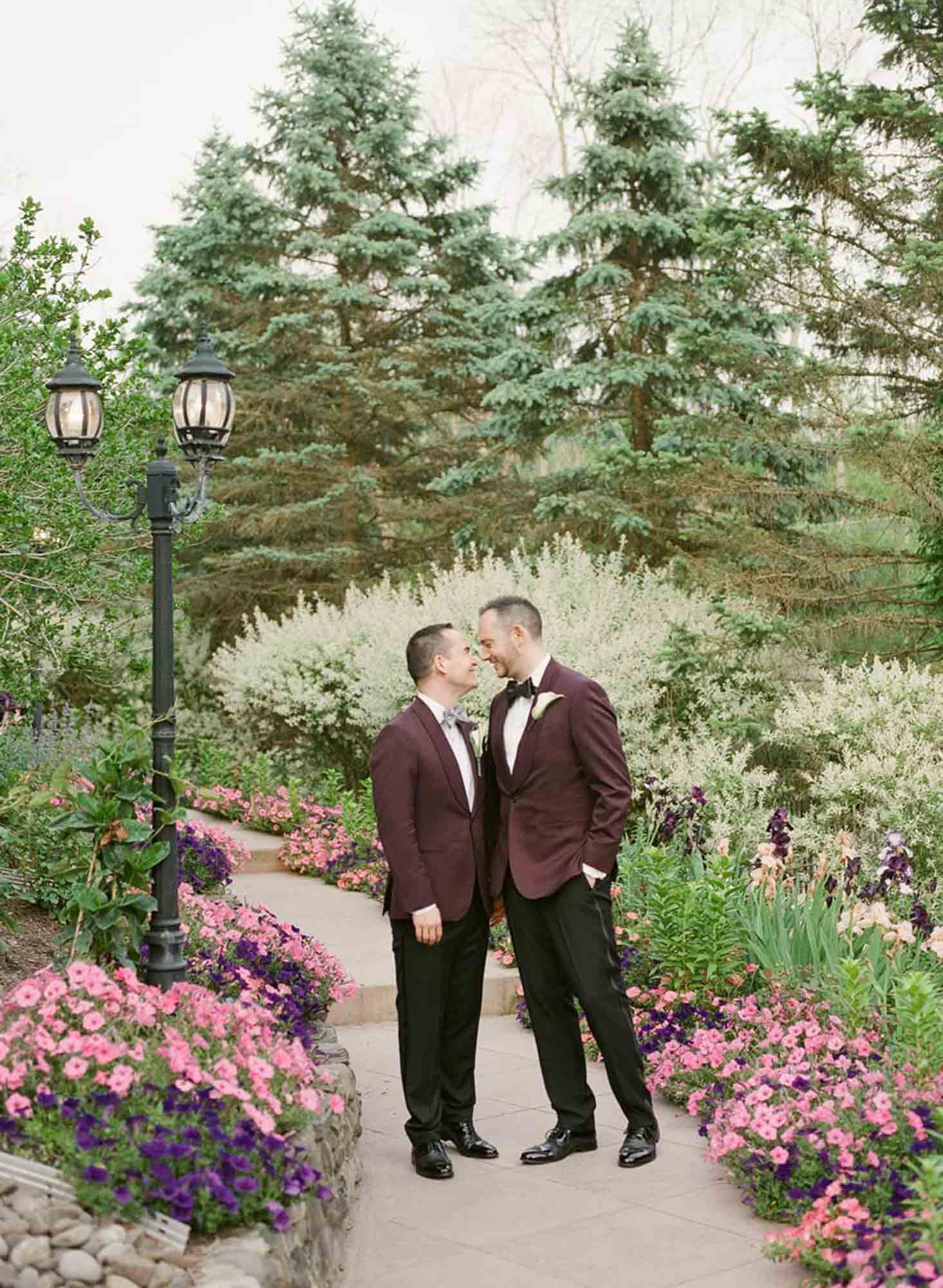 men in love grooms in purple jackets holding hands LGBTQ+ wedding featured on Equally Wed magazine with two grooms Brian + Brett: Hudson Valley garden wedding with shades of purple Upasana Mainali Photography outdoor wedding ceremony