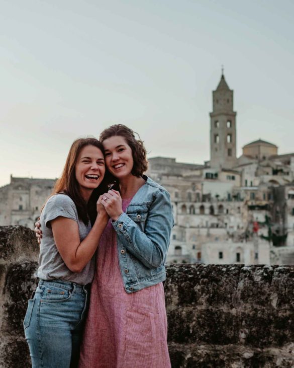 LGBTQ+ sunset proposal in Matera, Italy image description: two women hold hands smiling after one proposed to the other