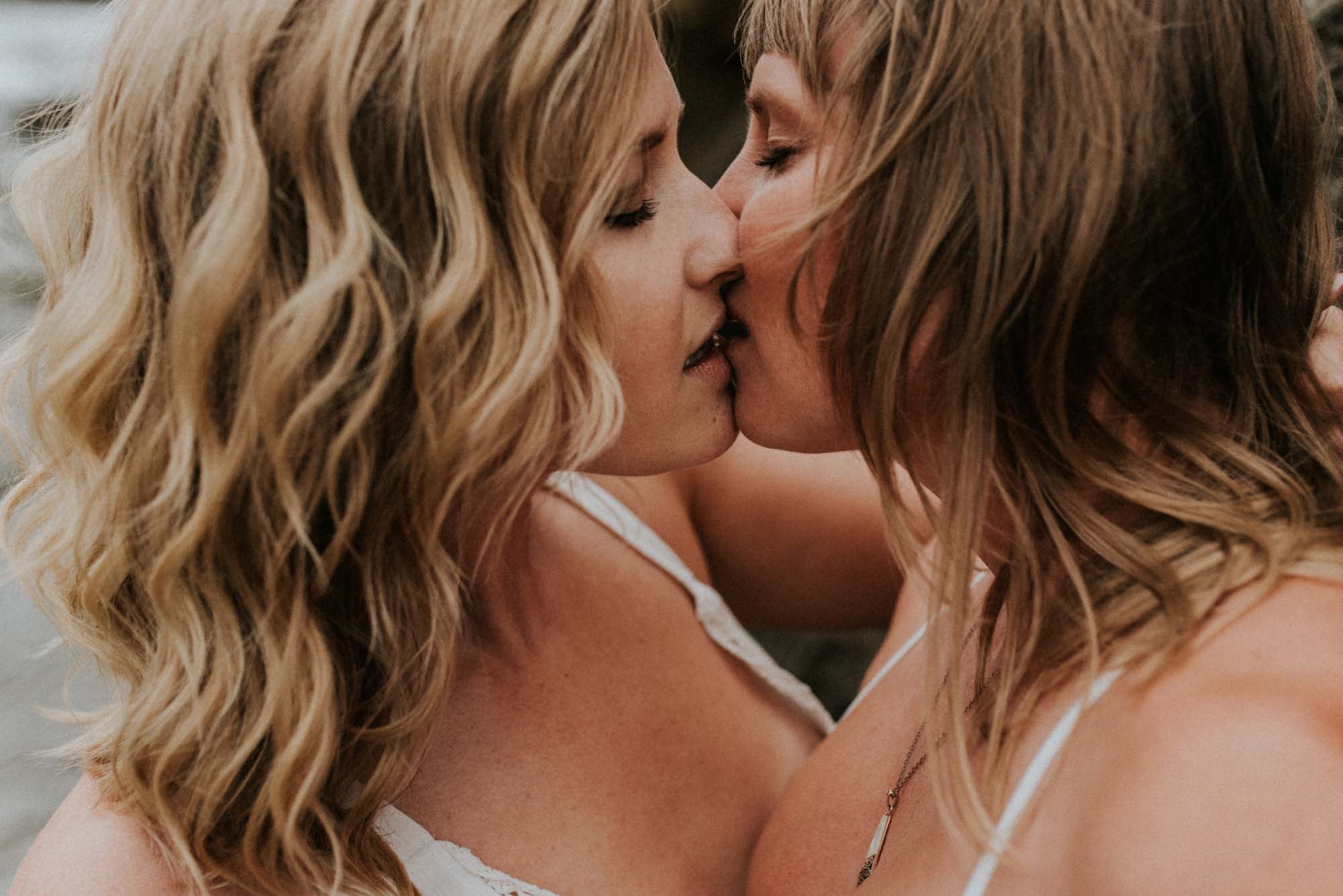 Magical engagement photo session in Big Sur. Photography by Heather K. Purdy. Featured on Equally Wed, the leading LGBTQ+ wedding magazine and wedding vendor directory of LGBTQ+ inclusive wedding pros. romantic sexy image includes two blonde women in love in white outfits on beach