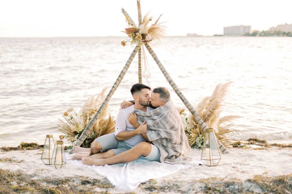 Seaside engagement inspiration with picnic, classic car, and handmade floral masks | Erica J Photography | Featured on Equally Wed, the leading LGBTQ+ wedding magazine