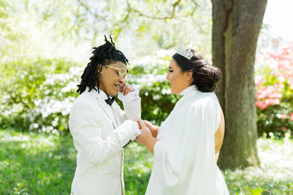 Sunny South Carolina elopement surrounded by greenery | Jessica Hunt Photography | Featured on Equally Wed, the leading LGBTQ+ wedding magazine -white tux, cut out dress, tiara, crown, gold rimmed glasses, first look
