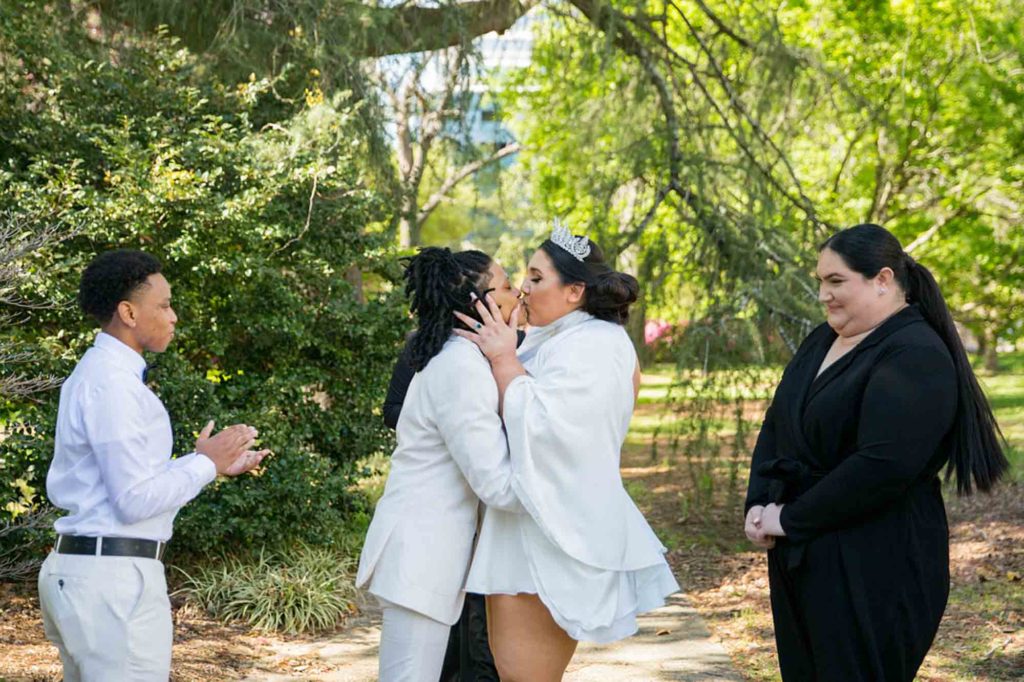 Sunny South Carolina elopement surrounded by greenery | Jessica Hunt Photography | Featured on Equally Wed, the leading LGBTQ+ wedding magazine - white tux, cut out dress, tiara, crown, gold rimmed glasses, kiss