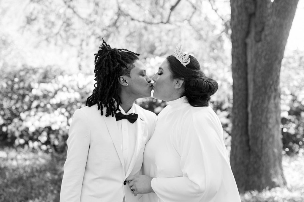 Sunny South Carolina elopement surrounded by greenery | Jessica Hunt Photography | Featured on Equally Wed, the leading LGBTQ+ wedding magazine - white tux, cut out dress, tiara, crown, gold rimmed glasses