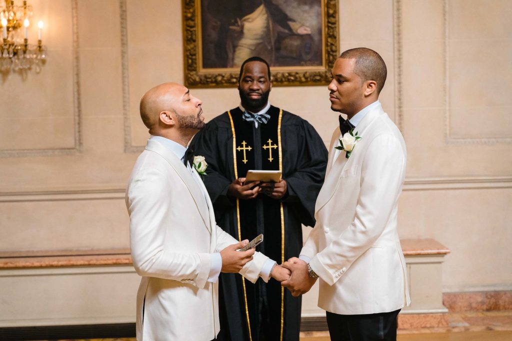 This couple transformed their home into a fabulous wedding venue | Myron Fields Photography | Featured on Equally Wed, the leading LGBTQ+ wedding magazine - ceremony, white tuxedos, holding hands, grooms