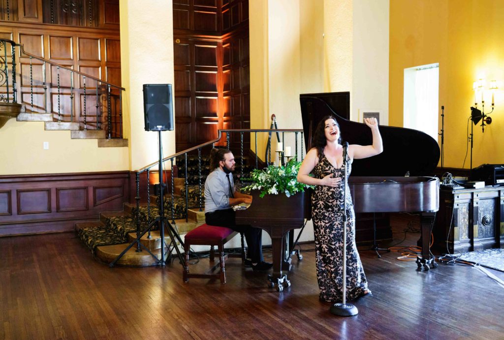 woman singing at a wedding while pianist plays in background