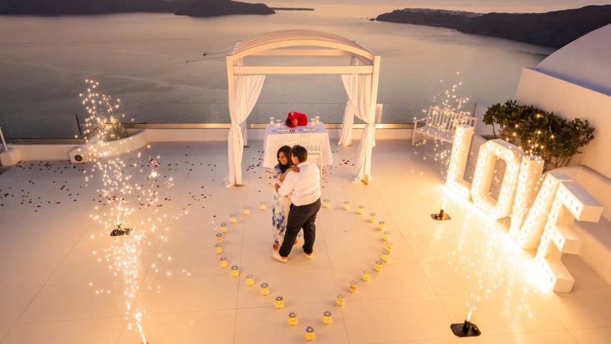 Breathtaking Santorini proposal with rose petals and a heart made of candles