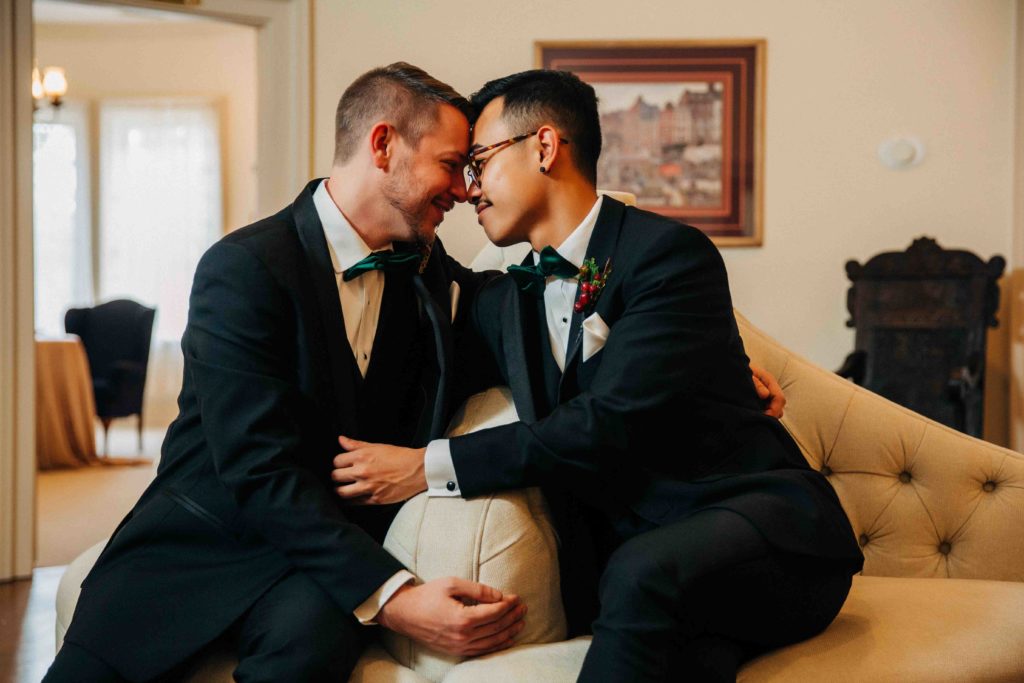 two grooms lean in touching foreheads, gay wedding