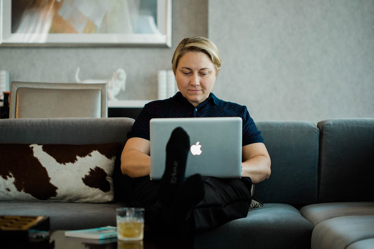 white nonbinary person with blonde hair sitting on couch with laptop