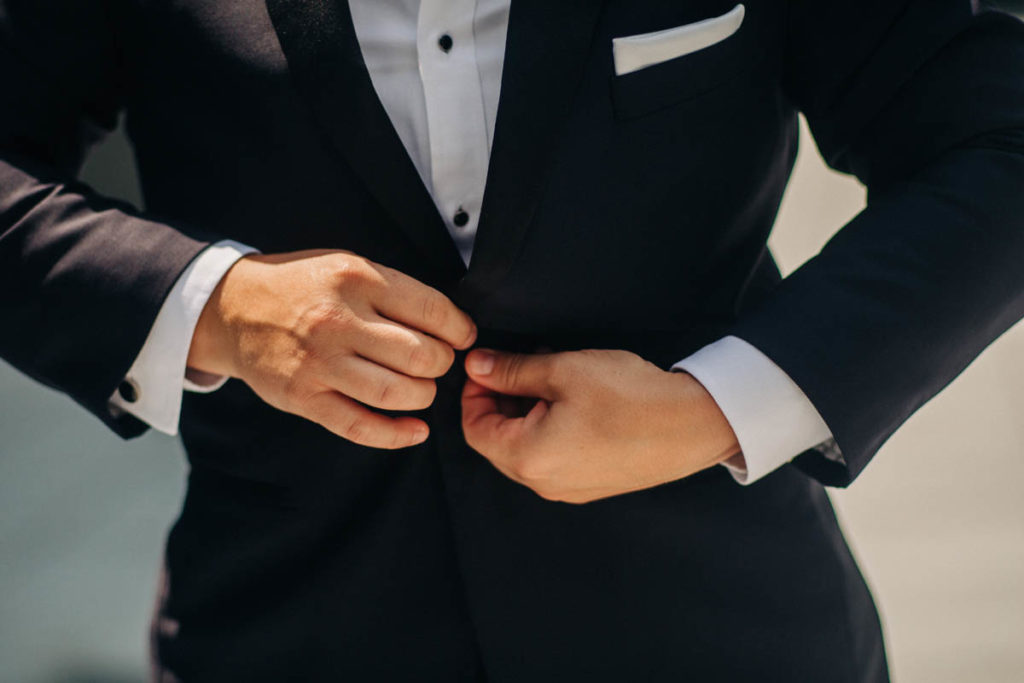 nonbinary person buttoning tuxedo suit jacket