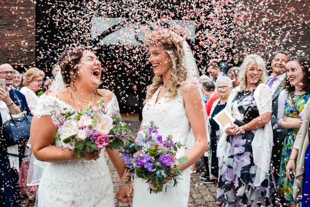 brides celebrate after their ceremony with confetti