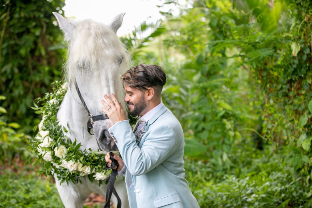 groom in blue suit pets white horse