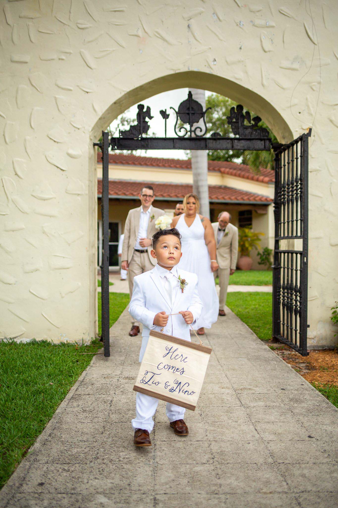 wedding procession with young boy holding a sign