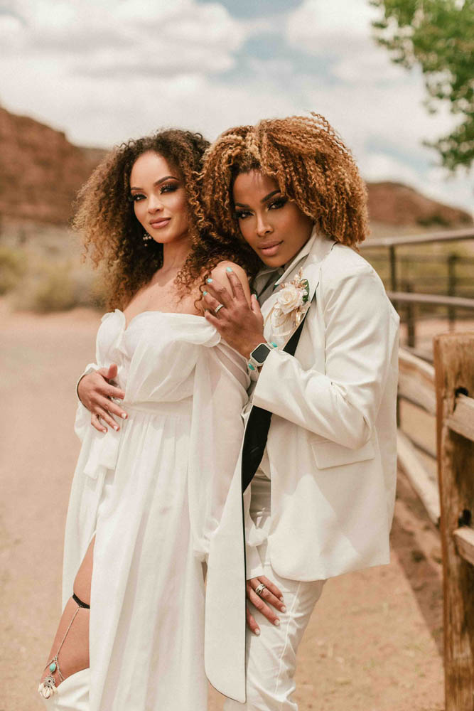 Lesbian marriers pose for camera while standing at a ranch.