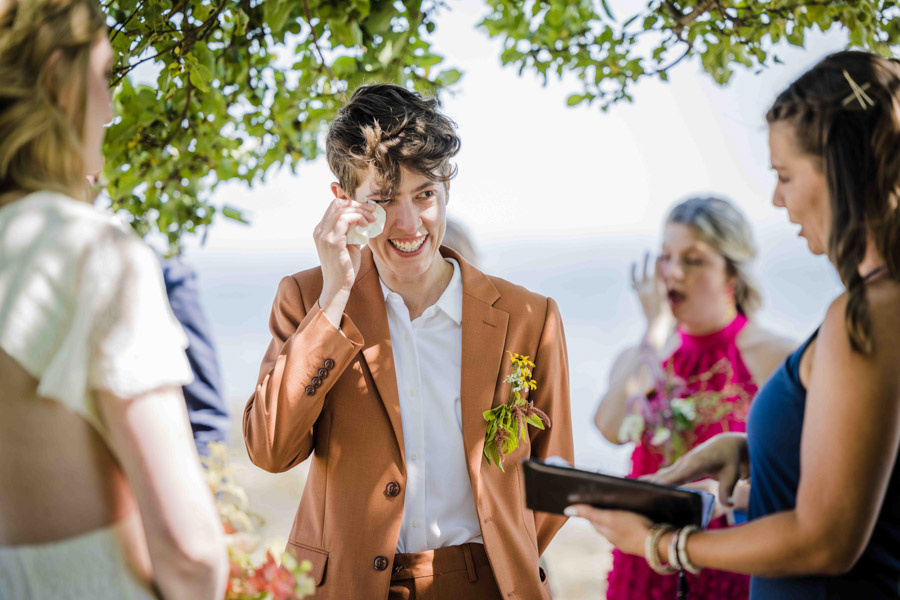 brunette genderfluid marrier wipes their eyes during their wedding ceremony