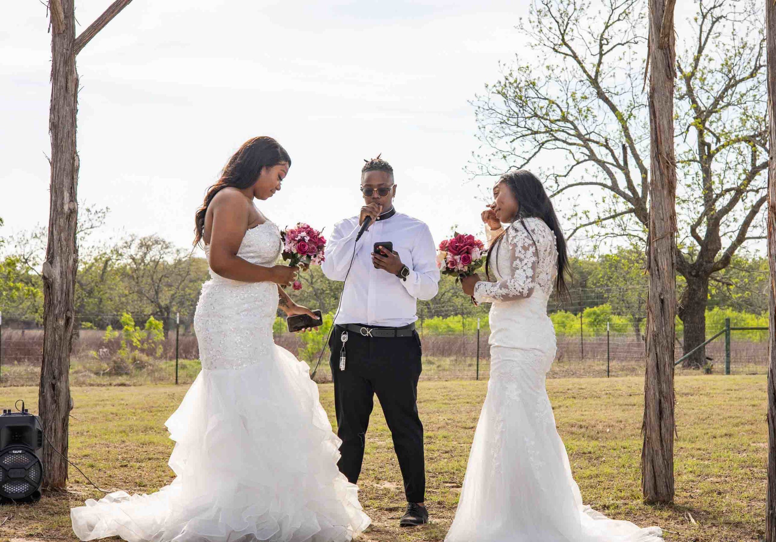 two Black lesbian brides exchange vows, both are wearing white wedding gowns