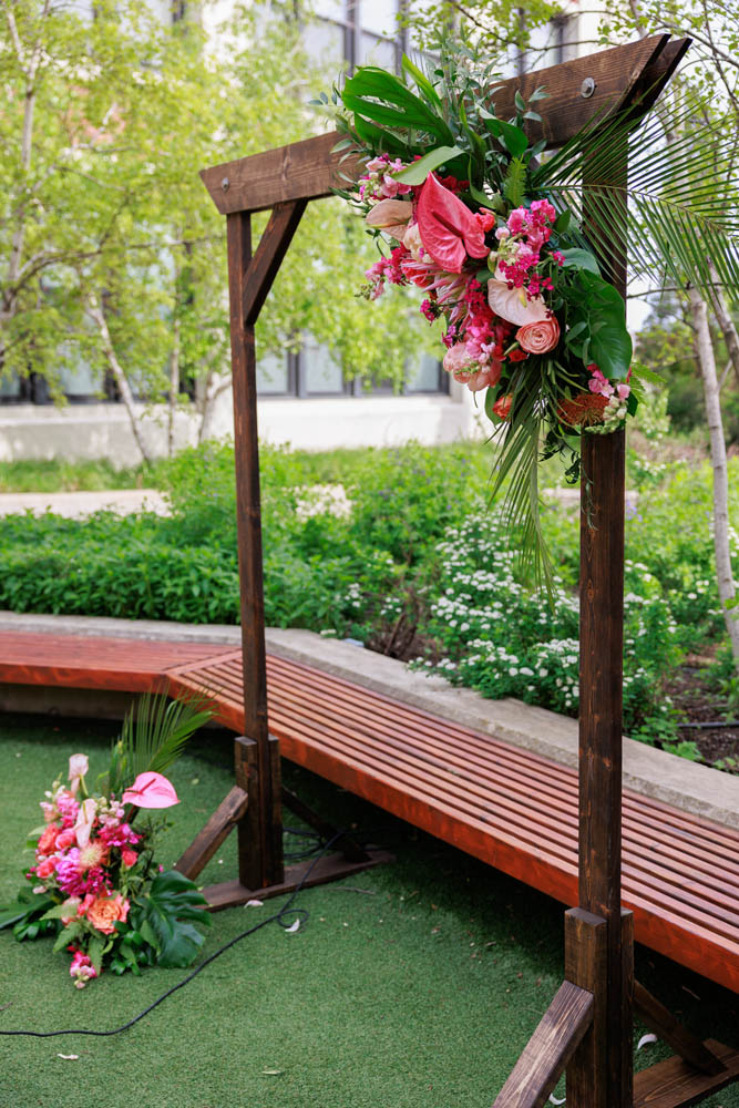 wooden wedding arch decorated with tropical pink flowers