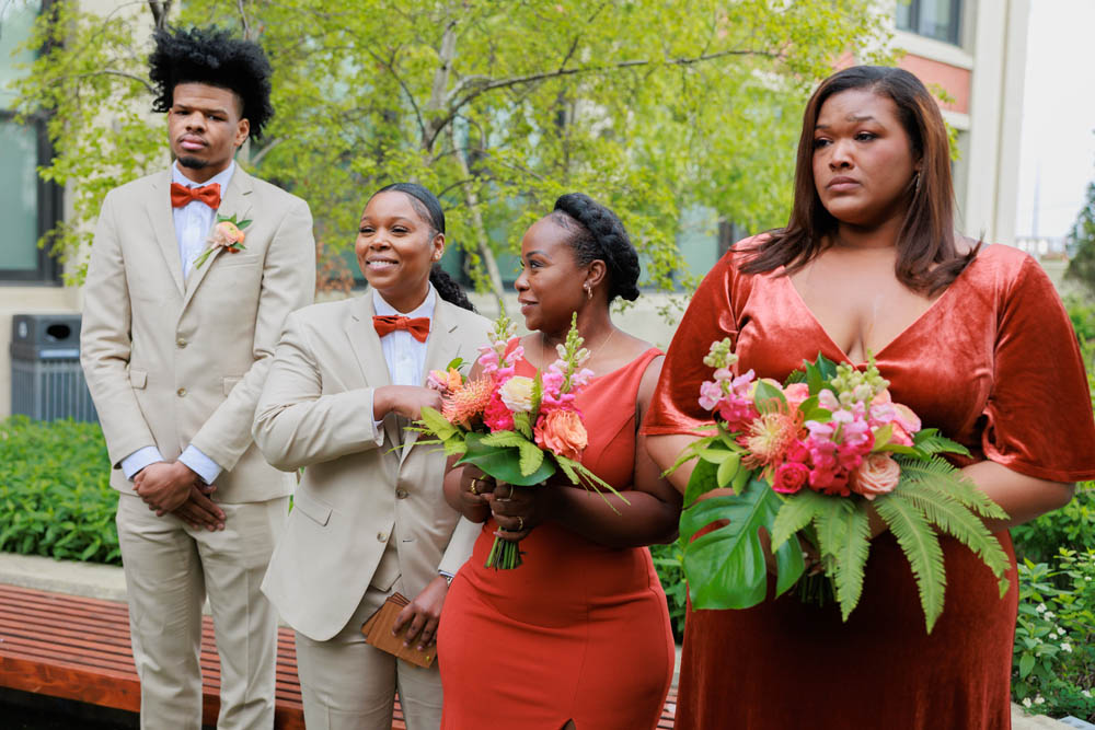 Black wedding attendants of varying genders in cream suits and dark orange gowns for LGBTQ+ Chicago wedding