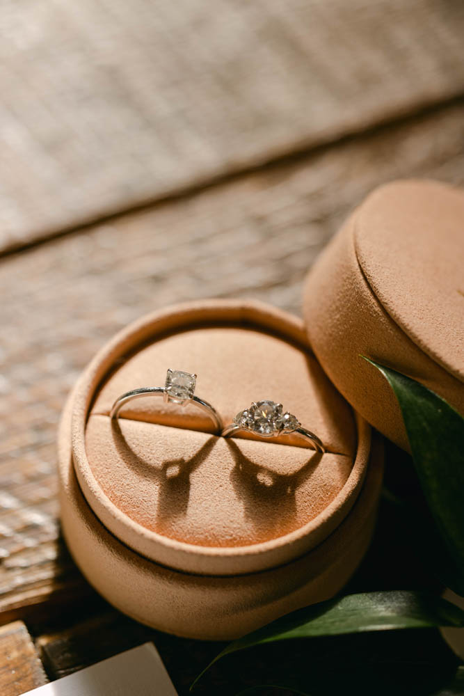 two women's wedding rings in a peach satin circle box for two brides