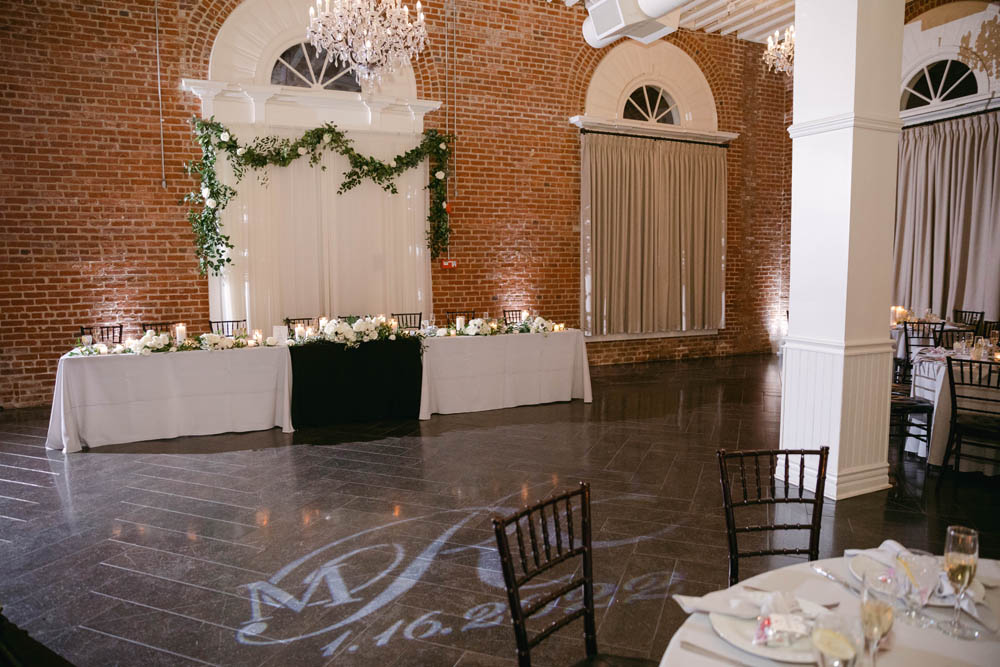 couple's initials in blue lights on wedding floor with wedding decor around it