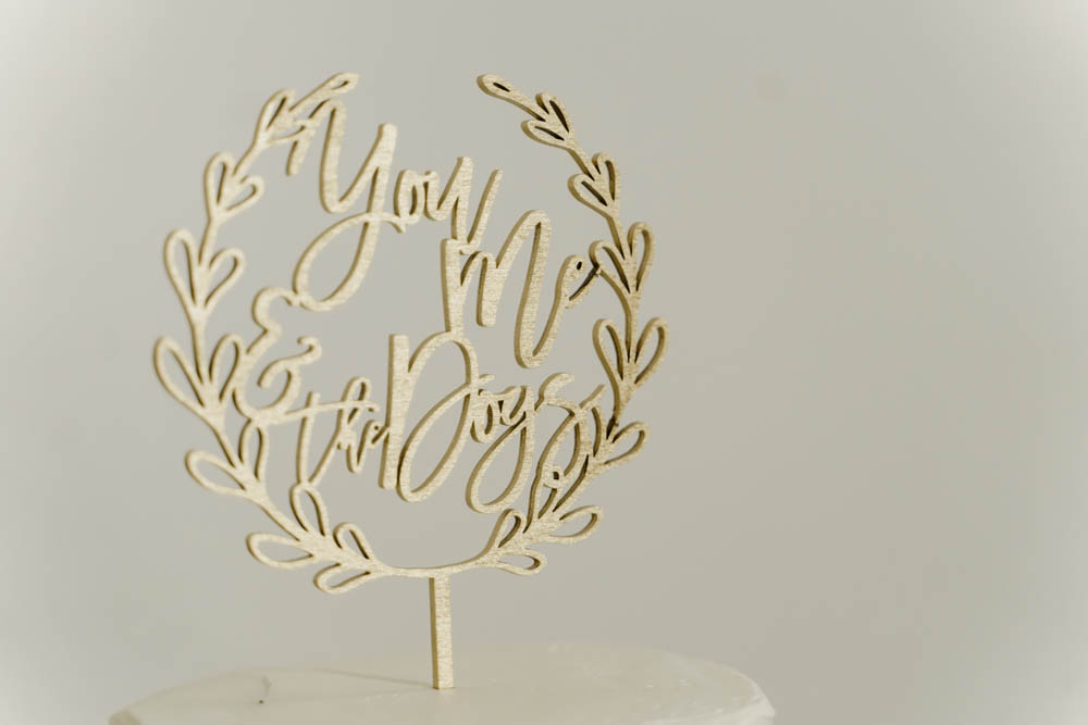 gold wedding cake topper that reads: You, Me and the Dogs