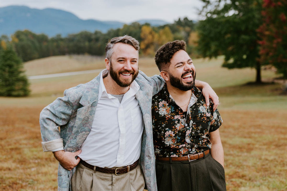 two men in love smiling and laughing in a mountain field