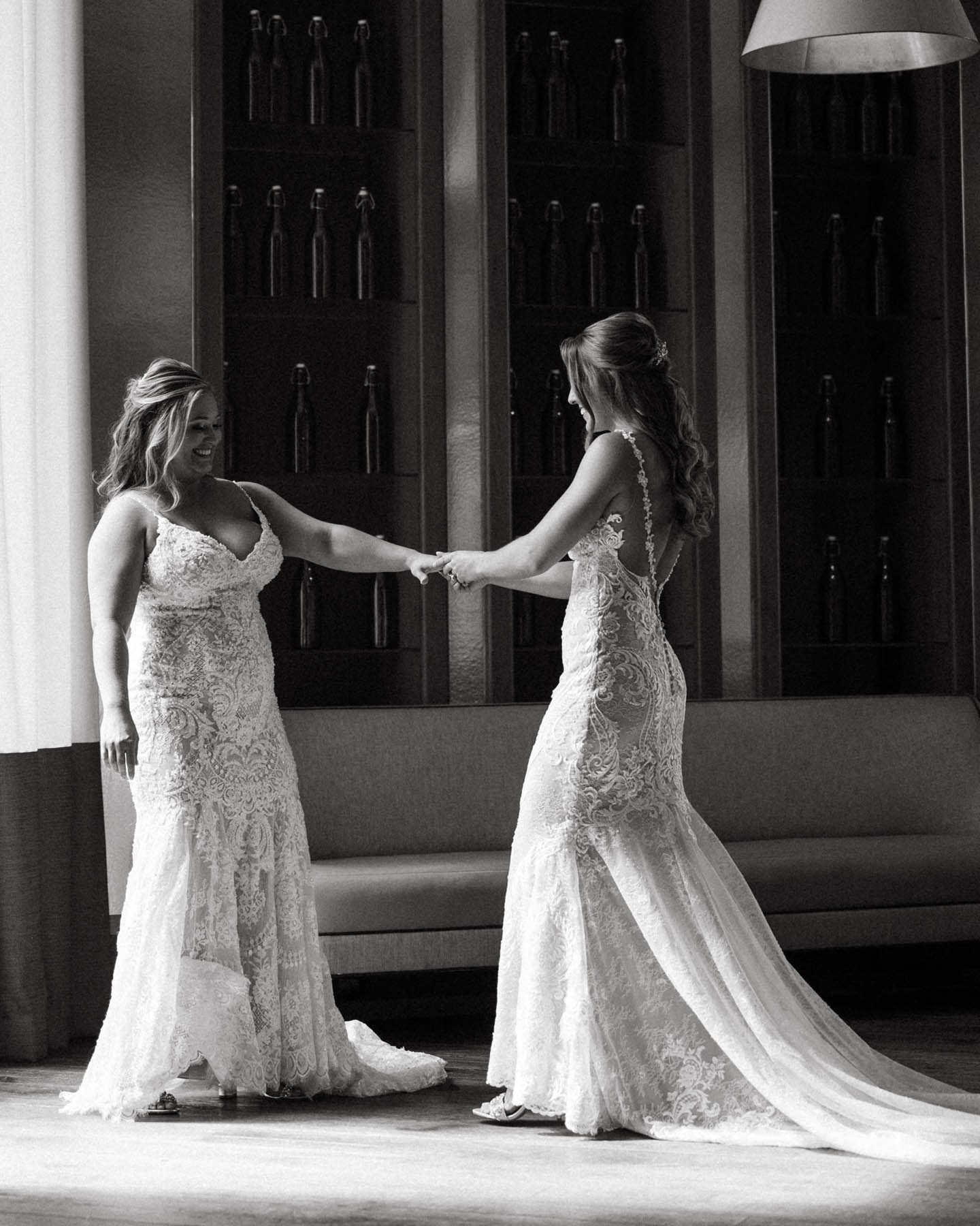 A black-and-white image of the brides holding hands as they have their first look.