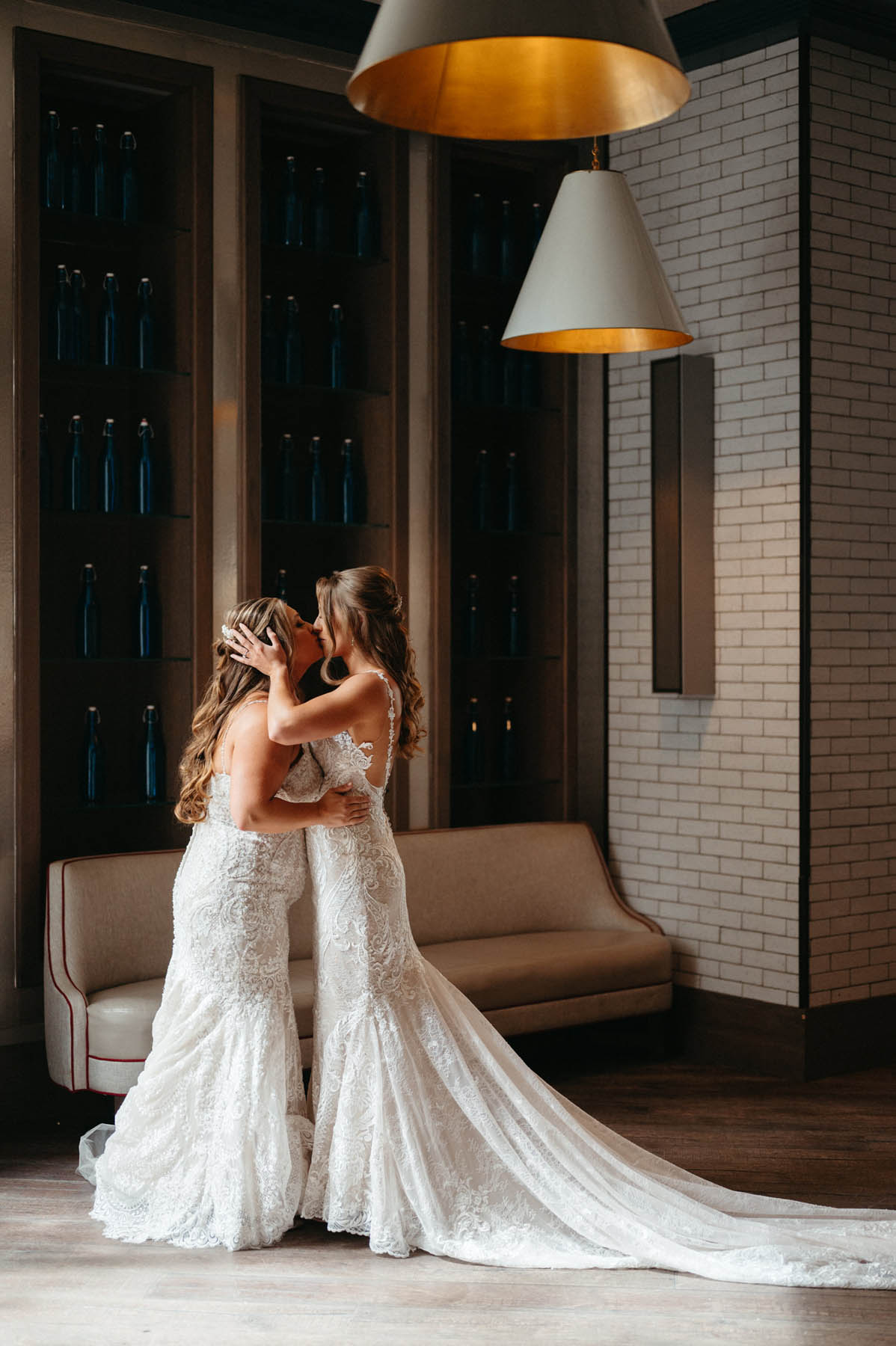 The brides kiss as they stand in their lace white gowns.