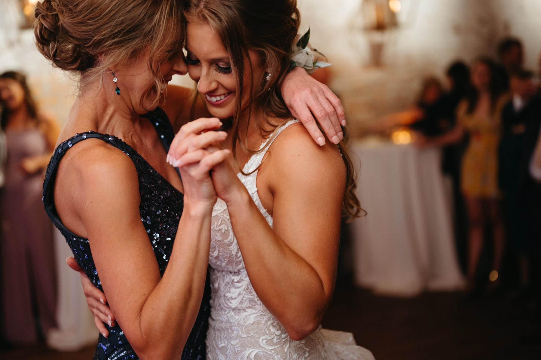 One of the brides dances with a woman wearing a sparkly blue dress.