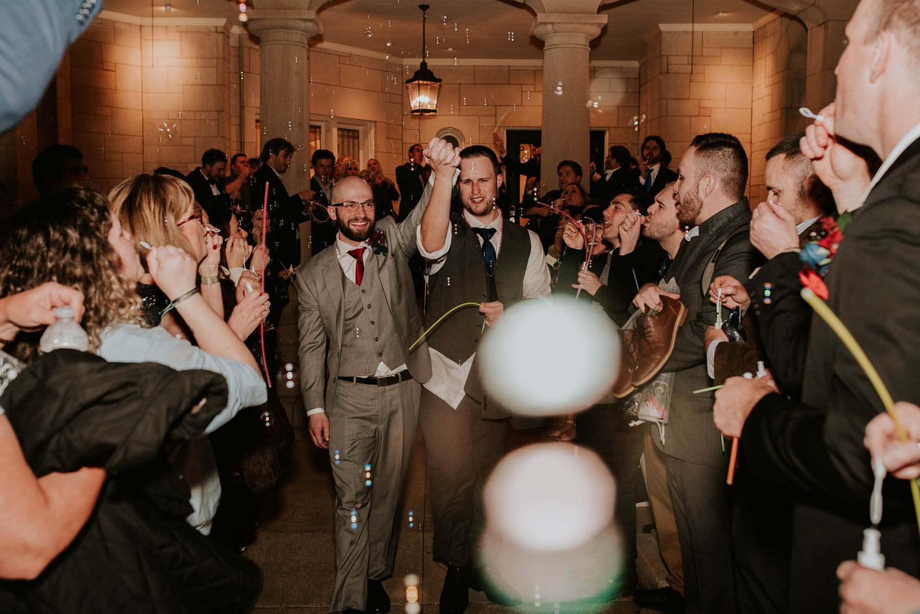The newlyweds walk down an aisle of their friends and family blowing bubbles and waving glowsticks as they leave the venue.