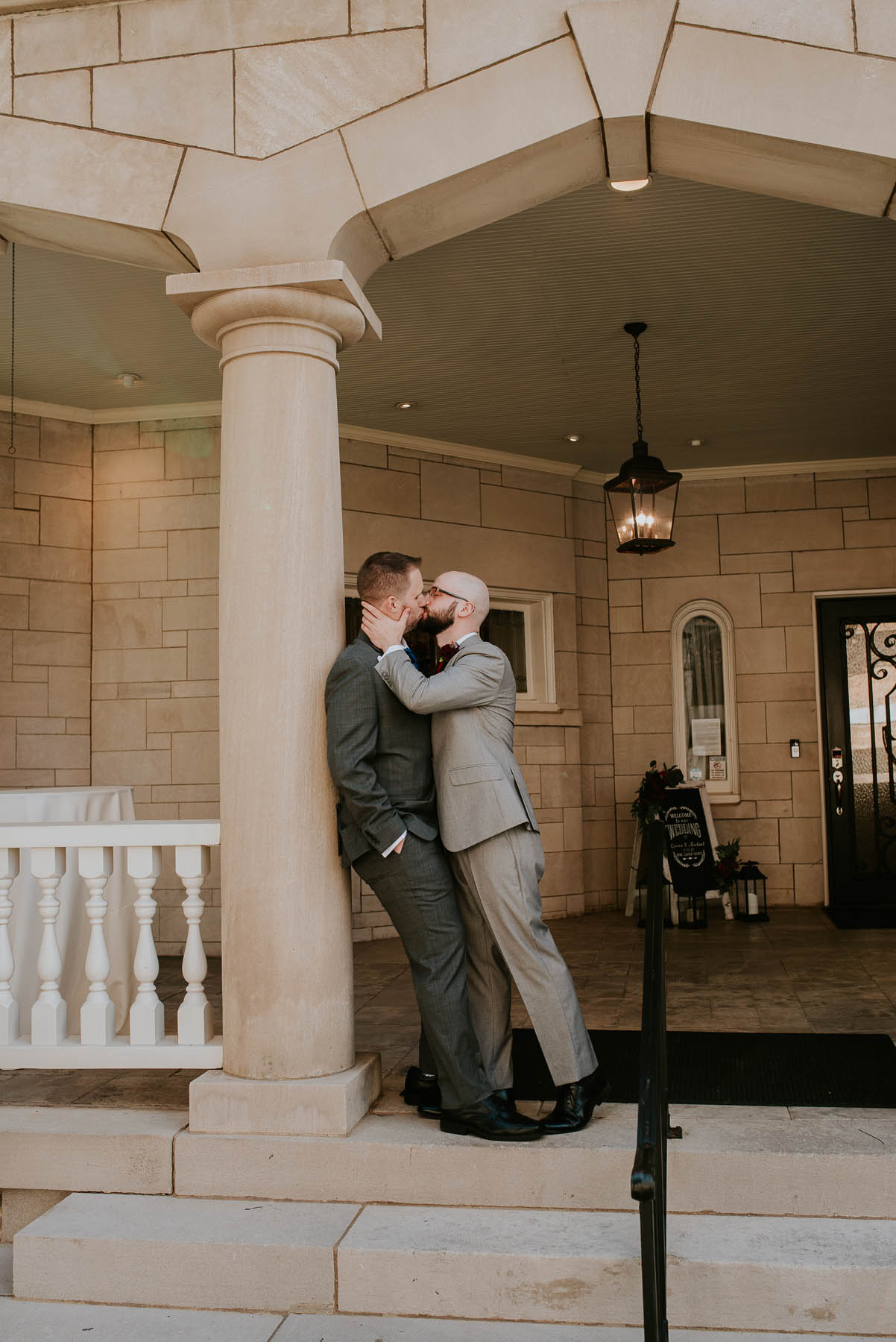 The newlyweds share a kiss outside the venue, with the masonry of the historic manor in the background.