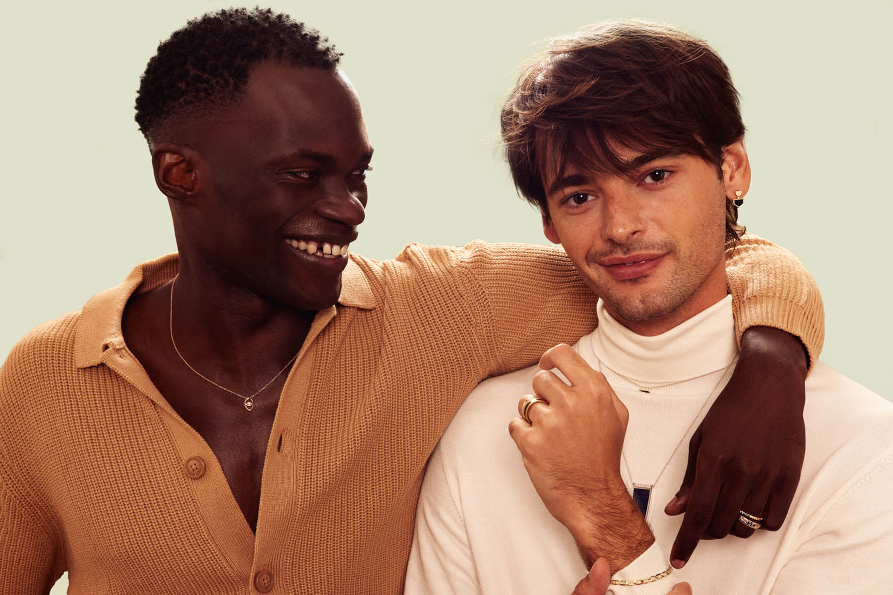 Two people model Bario Neal jewelry. The one on the left is wearing a necklace,a dn the one on the right is showing off a ring.