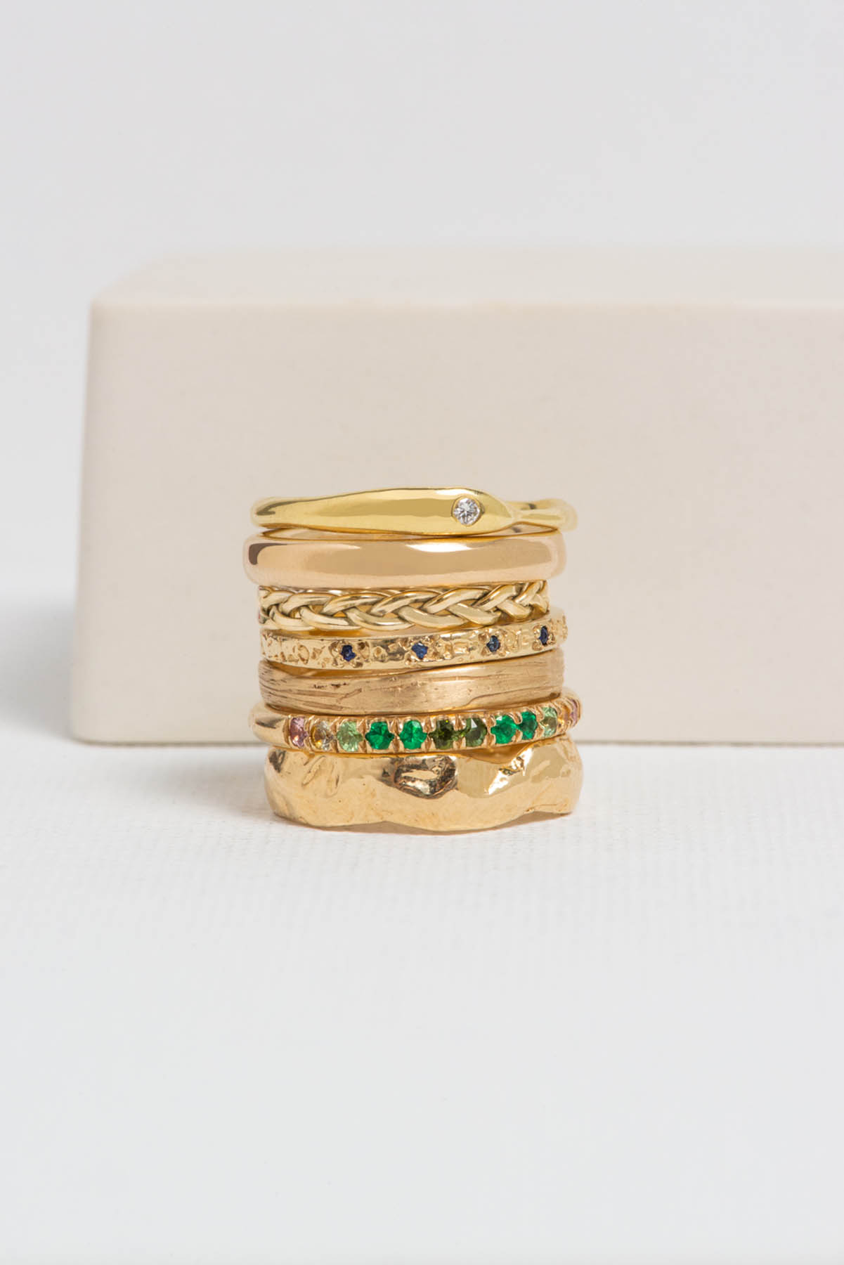 A stack of gold rings with green and clear accents.