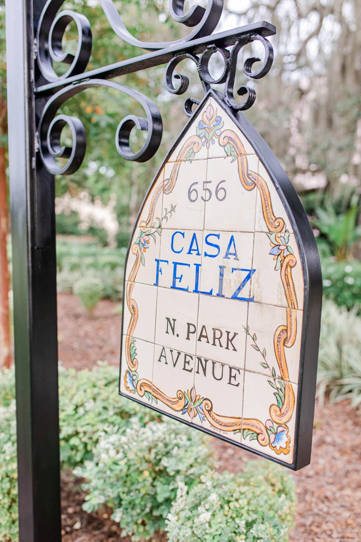 A tile sign hangs from a cast-iron post. The sign reads: 656 N. Park Avenue; Casa Feliz.