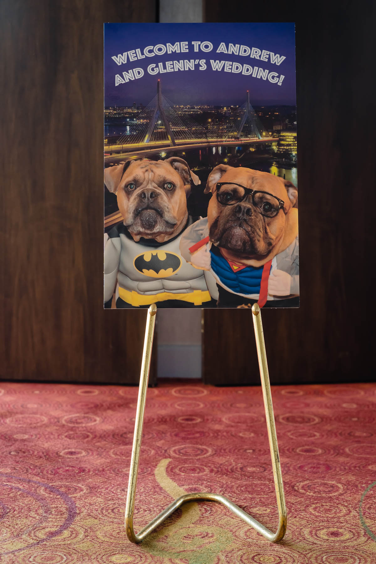 A welcome sign featuring the couple's two bulldogs, dressed as Superman and Batman, with text that reads: Welcome to Andrew and Glenn's Wedding!