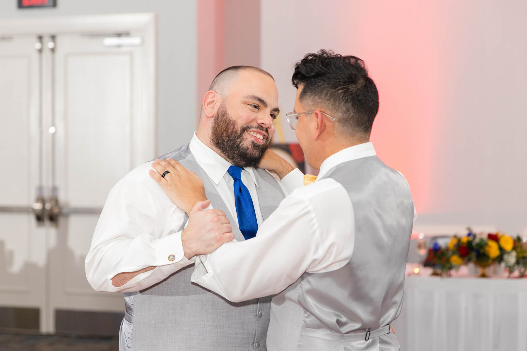 The grooms stand in the middle of the dance floor, gazing lovingly at each other.