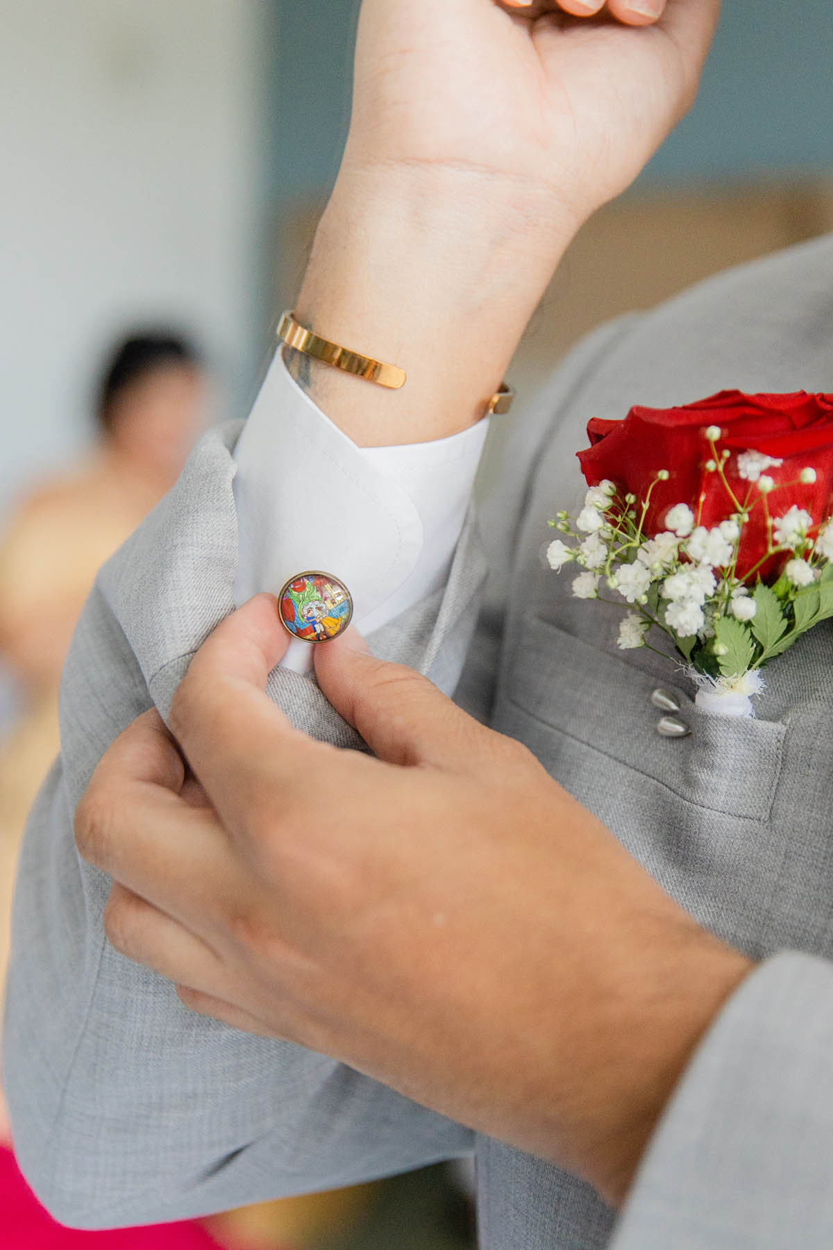 A groom puts on cuff links designed to look like stained glass.