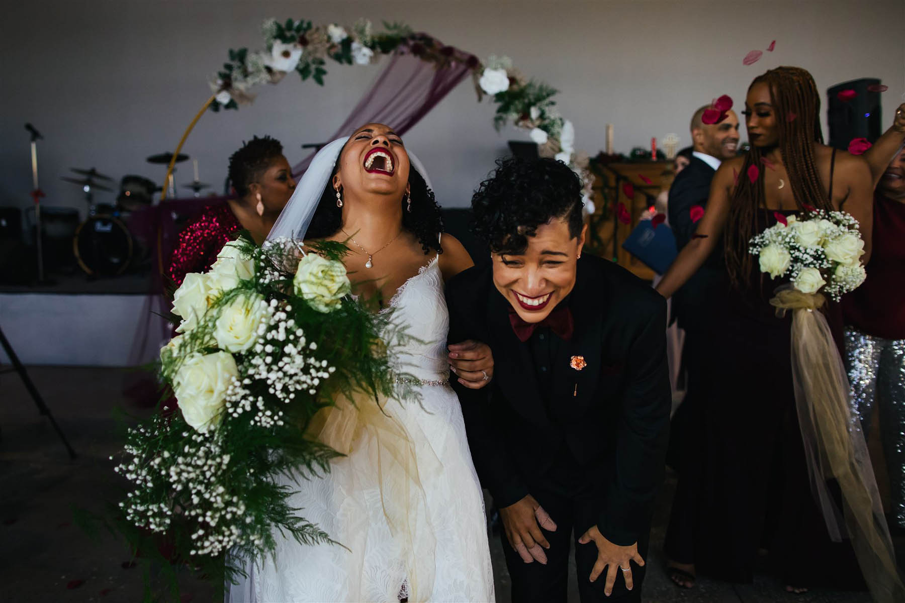 Two black brides laugh as they recede from their wedding altar. 
