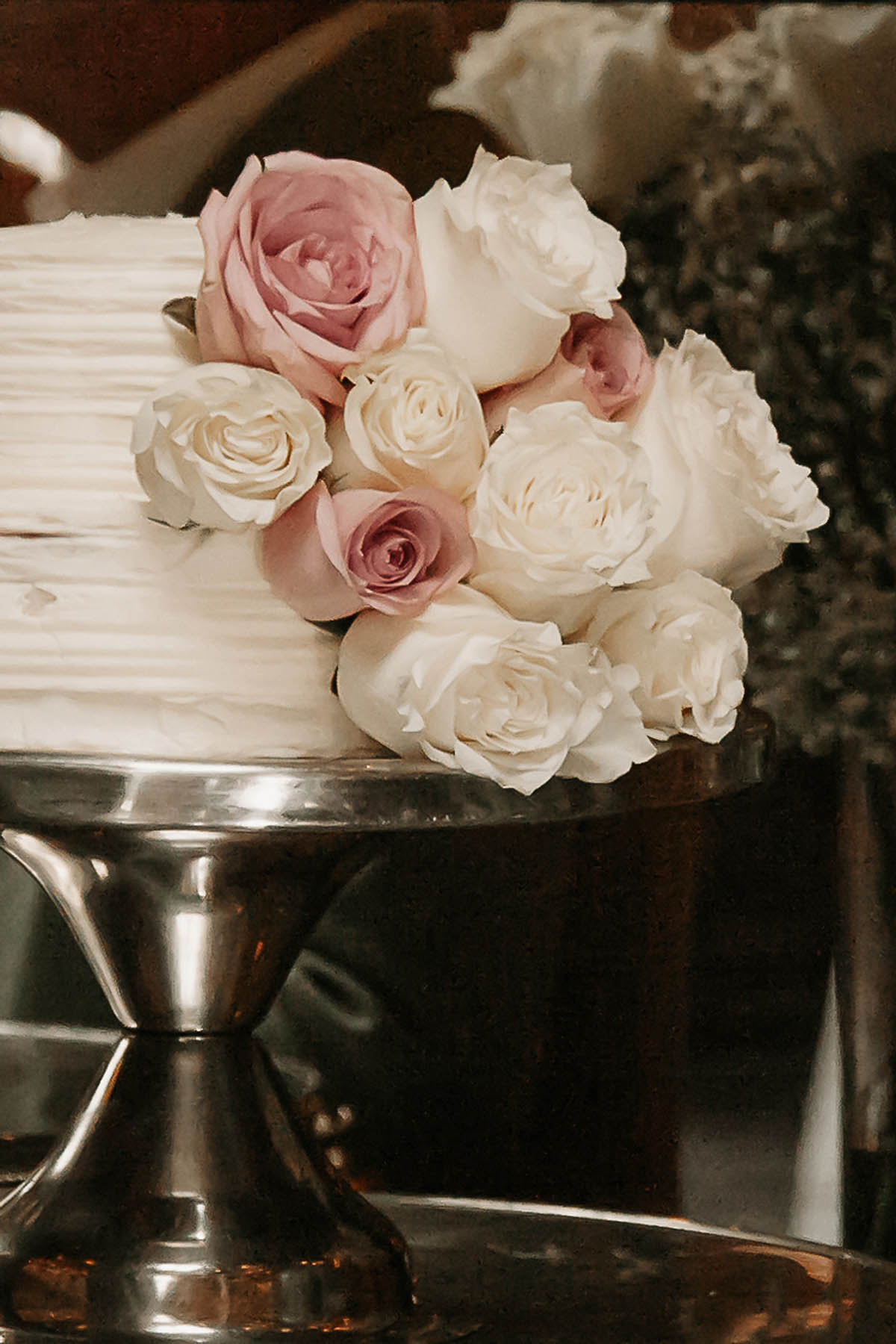 A two tier white cake with pink and white roses