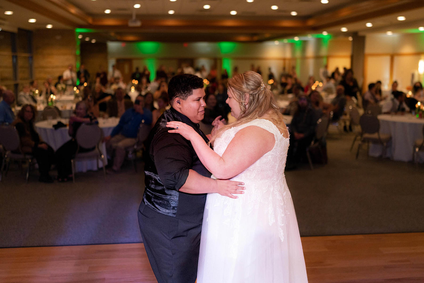 Two brides, one white and one black, share a first dance and gaze into each other's eyes.