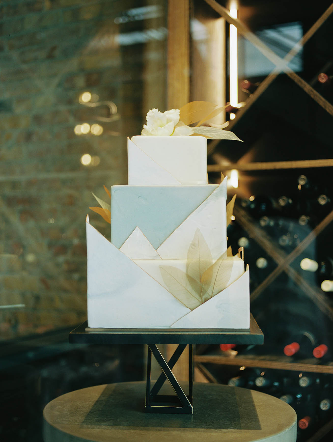A geometric cake with light green and ivory elements. 