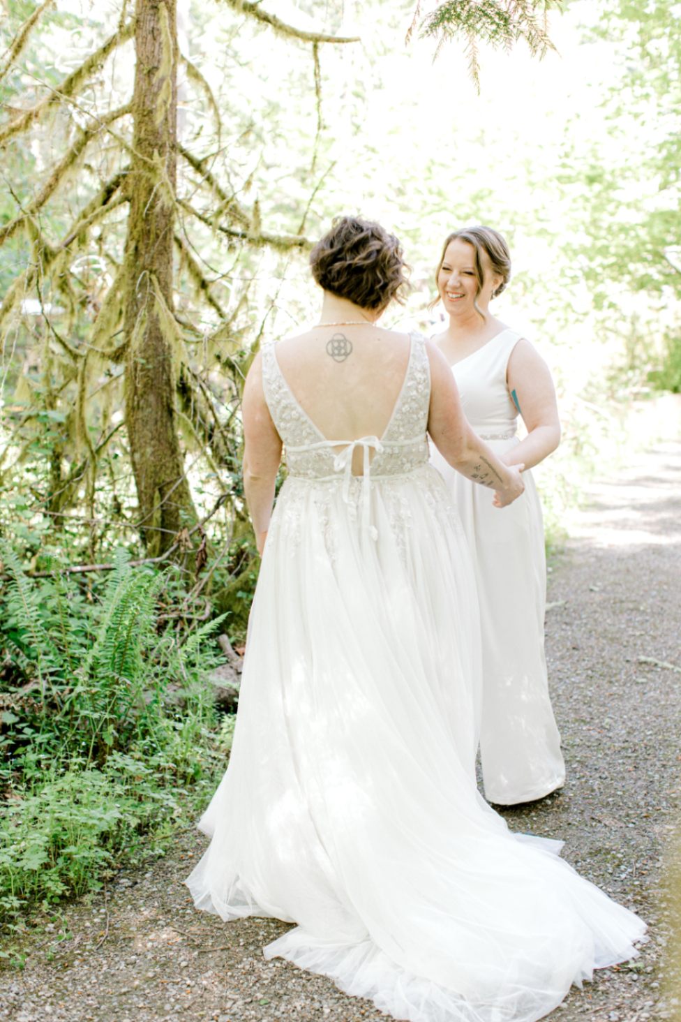 Two white lesbian brides in white wedding gowns with deep V-necks.