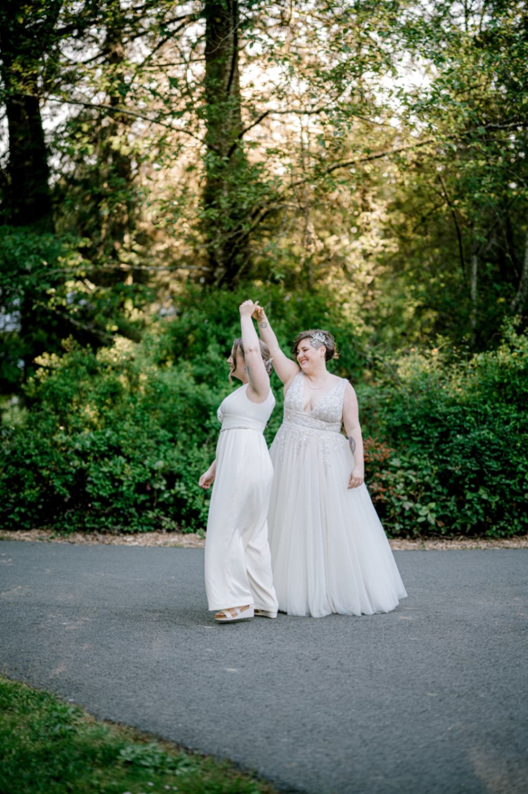 Two white lesbian brides dancing outside on their wedding day.