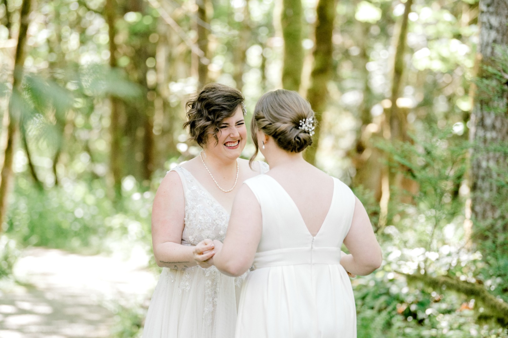 Two white lesbian brides in white wedding gowns with deep V-necks.