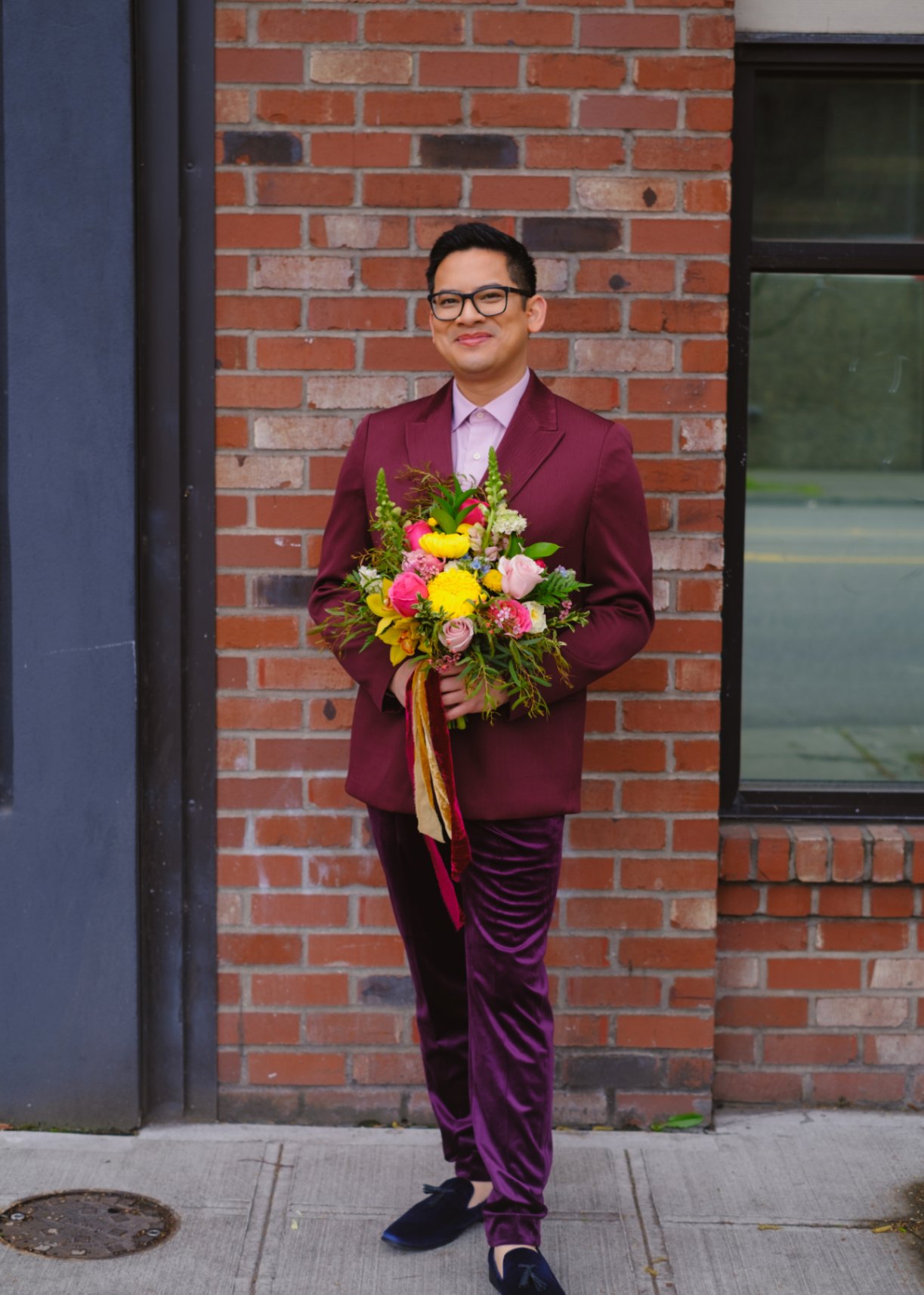 Seattle queer wedding styled shoot featuring a queer marrier wearing burgundy, pink and purple holding a colorful bouquet