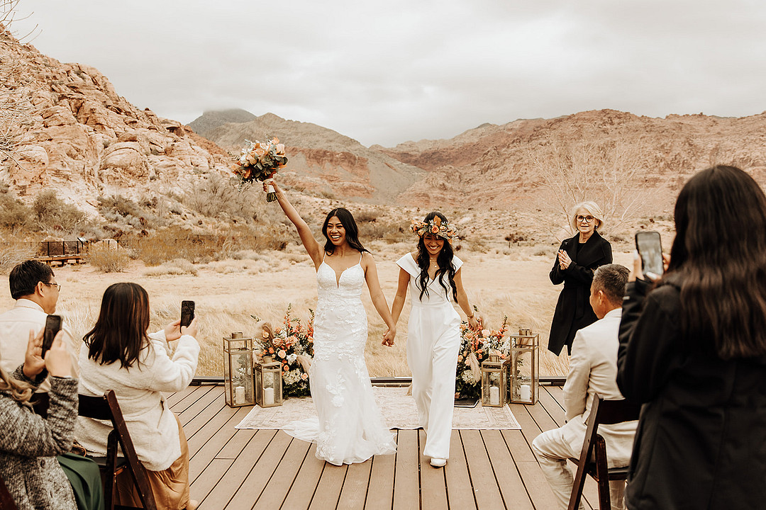 Lesbian wedding at intimate Red Rock Canyon elopement. The brides are smiling and the family is clapping.