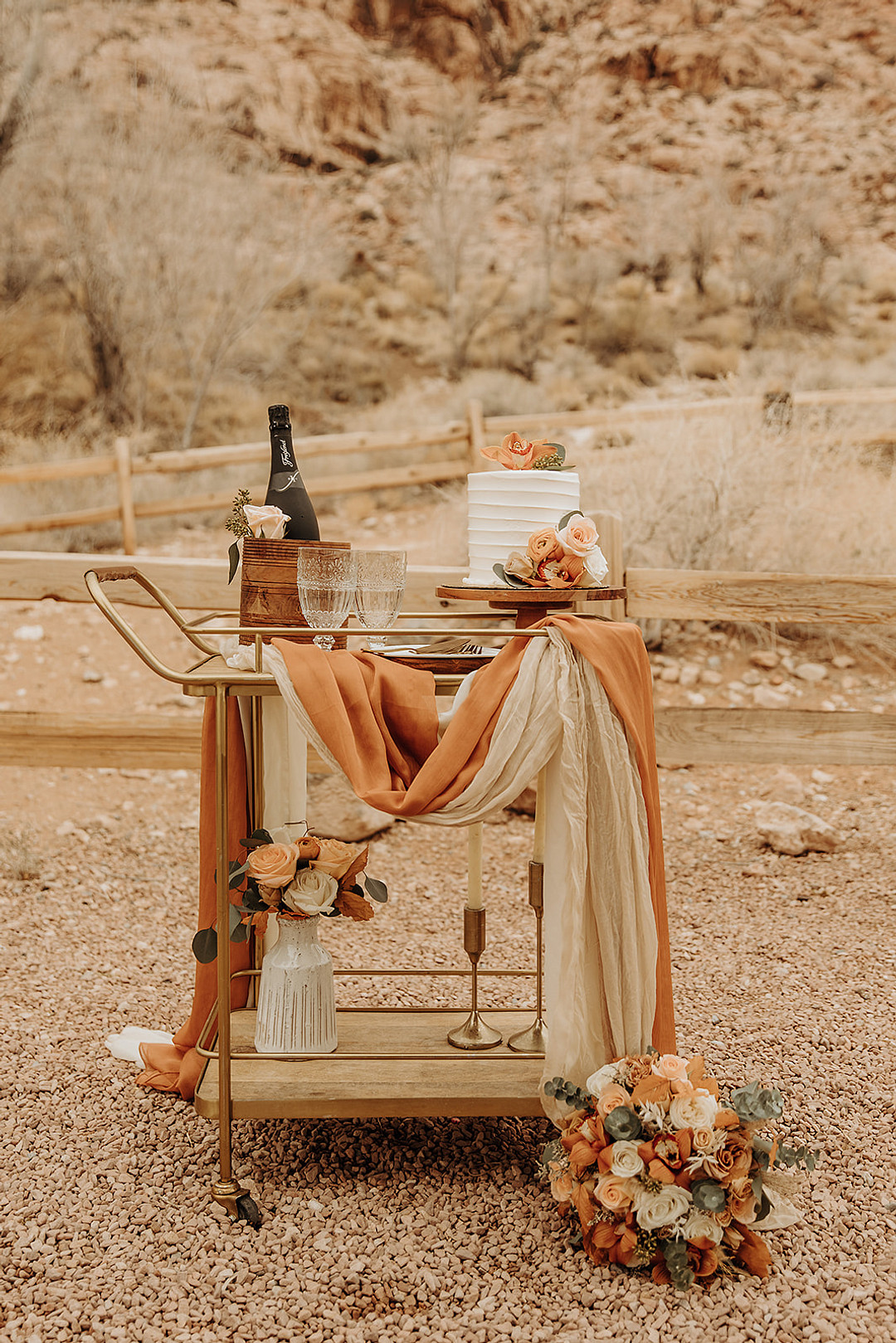 Bar cart for a wedding reception in Red Rock Canyon with champagne and a white wedding cake.