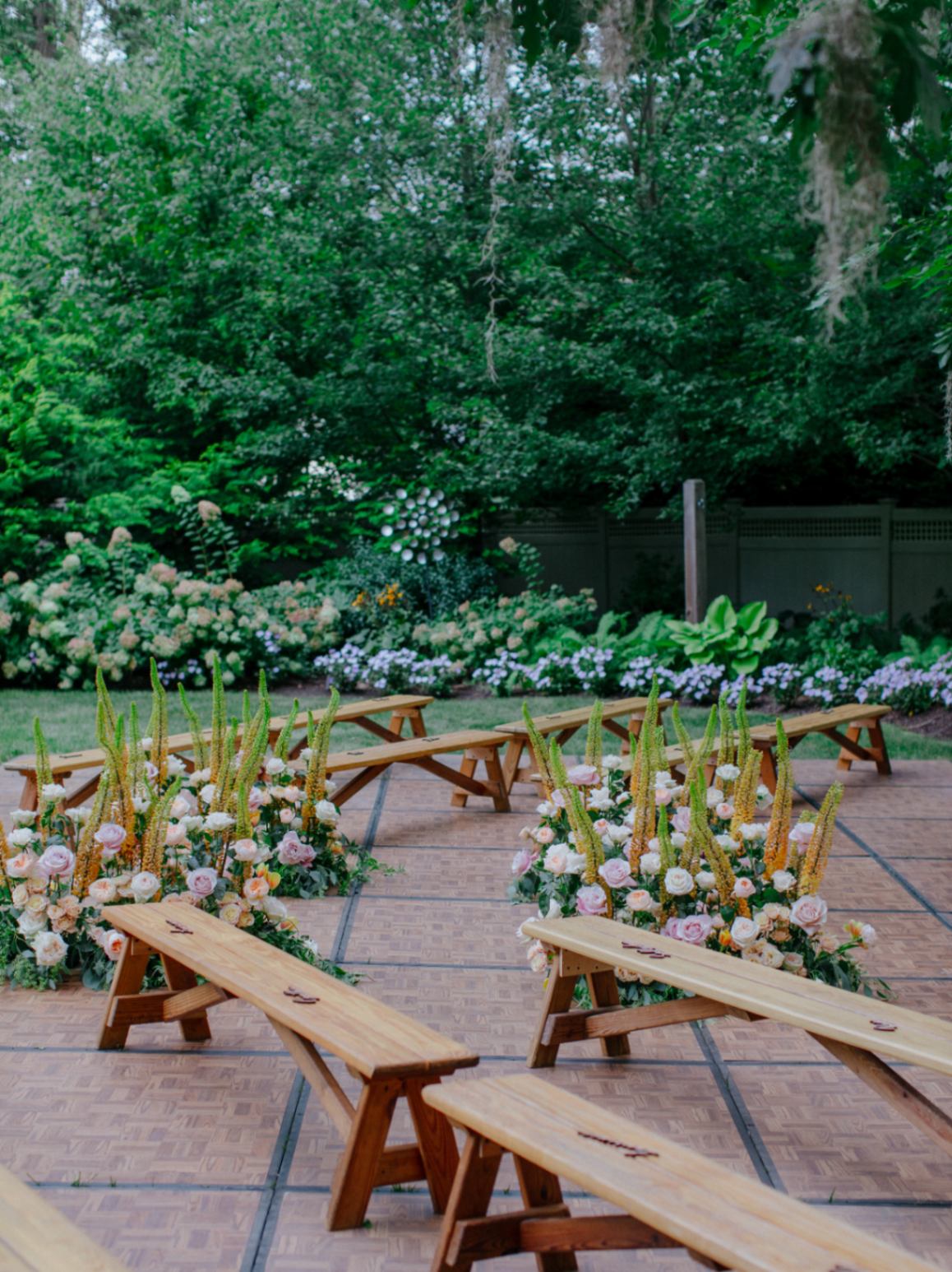 Outdoor wedding reception set up with wooden benches and flower arrangements