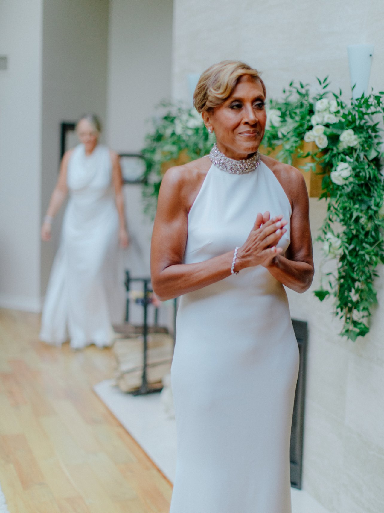 Celebrity lesbian couple Amber Laign, a white woman with blond hair, and her wife, Robin Roberts, a Black woman with light brown hair. Robin is waiting for Amber during their first look on their wedding day. Photo by Chris J. Evans