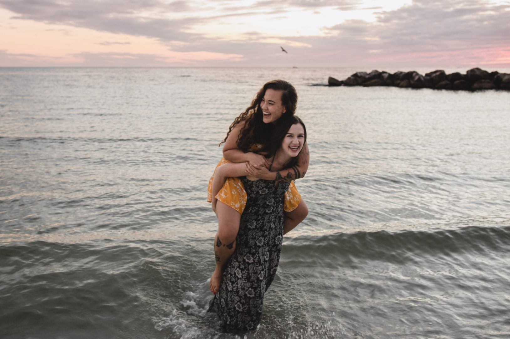 lesbian couple giving a piggyback ride in ocean