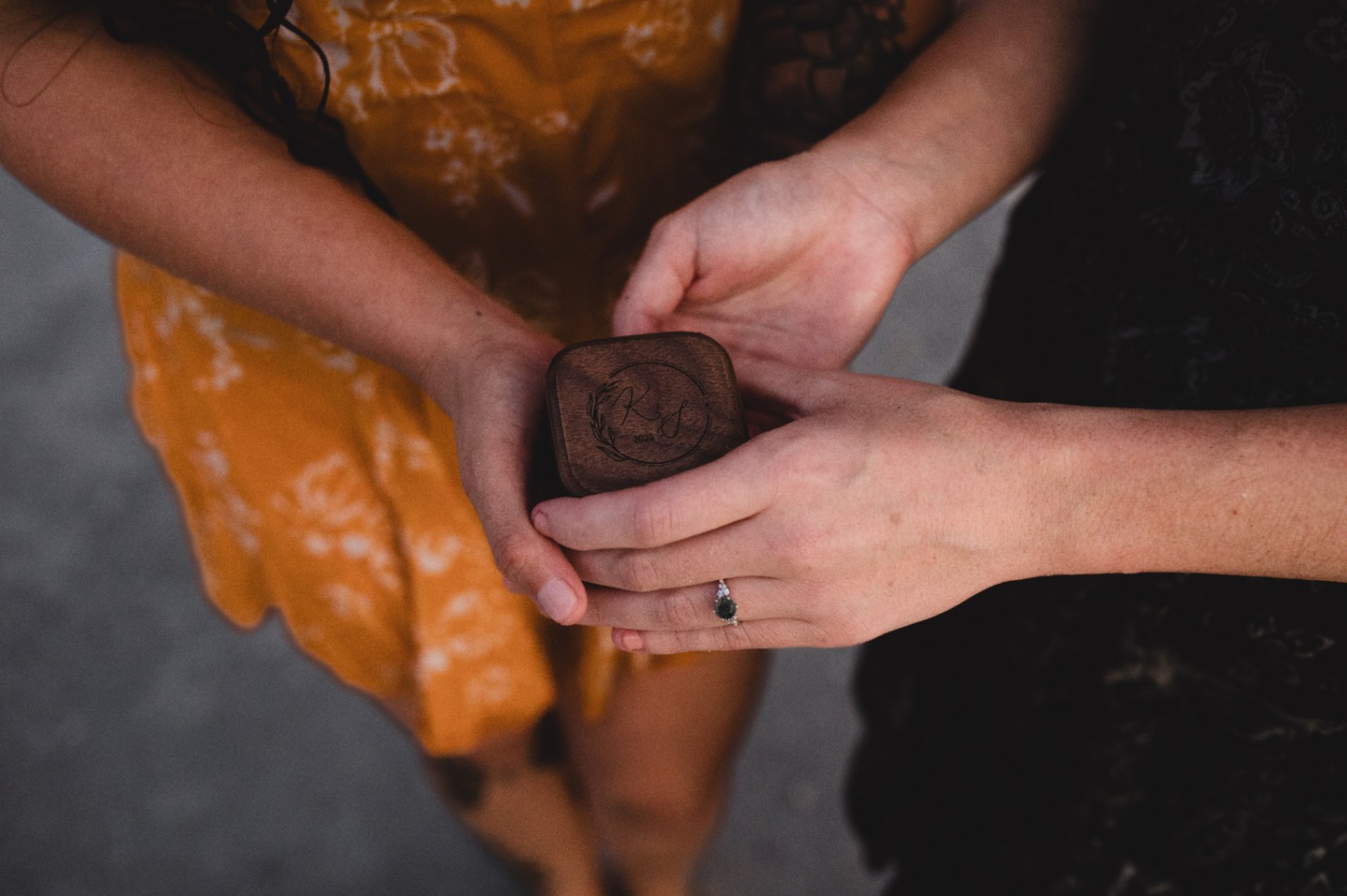 two engaged women hold a ring box